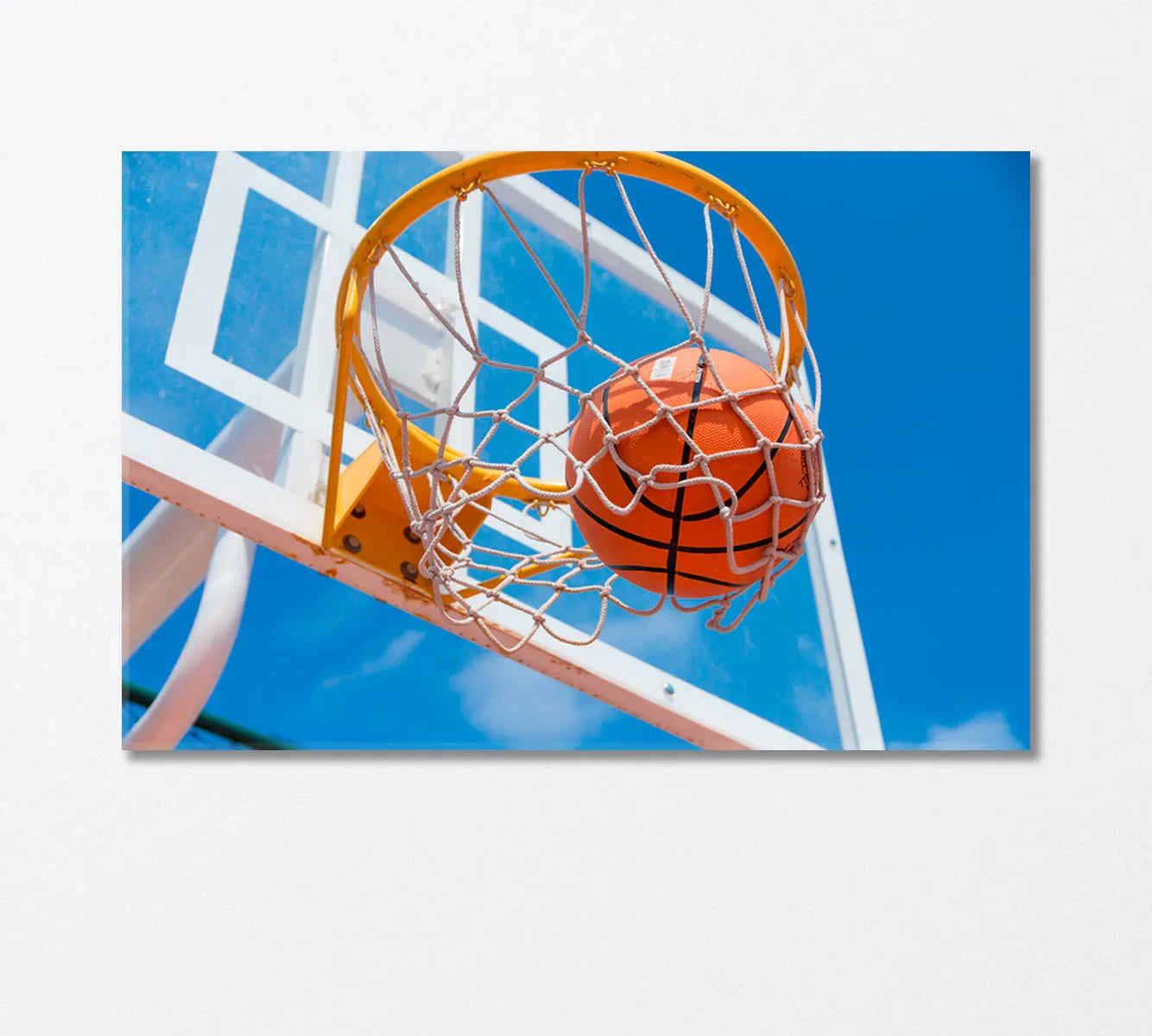 Basketball dropping through the net against bright sky — energetic canvas print